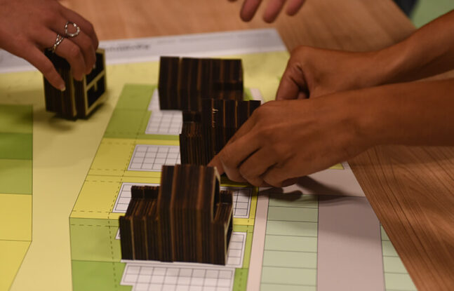 Handen verplaatsen miniatuurversie van een Tinyhouse op een bouwtekening