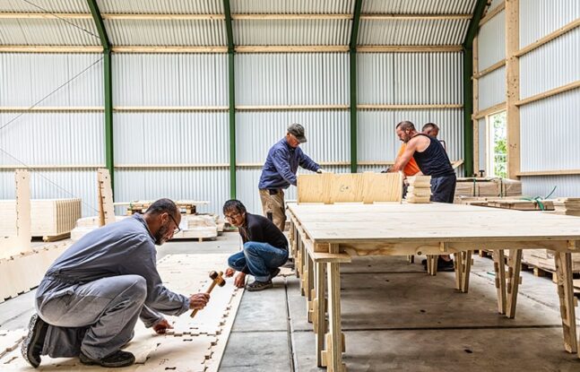 Werknemers werken in een loods aan de Wikihouse panelen - Maarten Feenstra