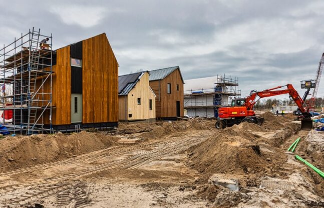 graafmachine graaft in grond naast Wikihouses in aanbouw - Maarten Feenstra
